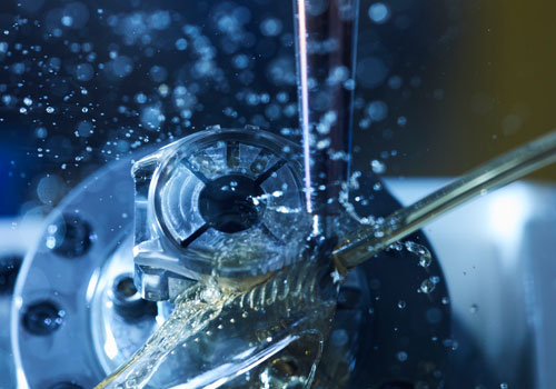 Nahaufnahme einer Werkzeugmaschine mit Wasser, das auf das Metallteil spritzt.