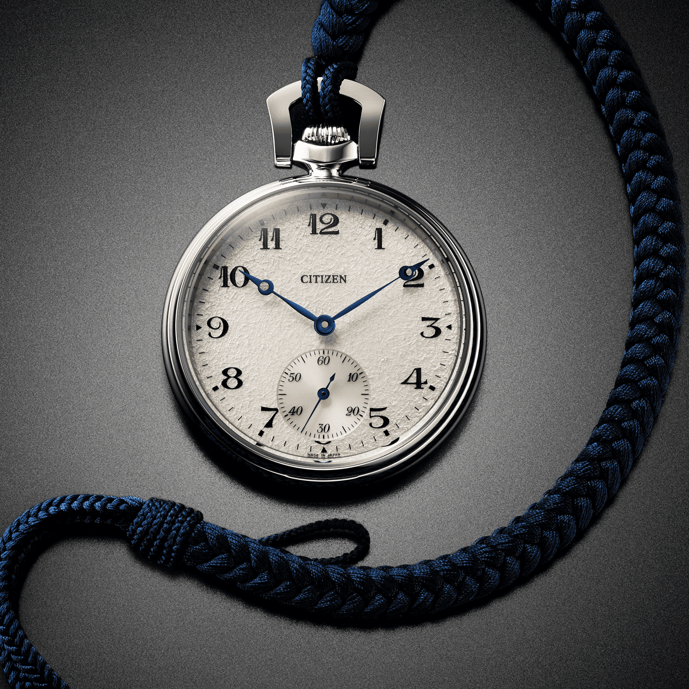 Nahaufnahme einer Citizen-Taschenuhr mit blau geflochtener Kordel auf grauem Hintergrund.