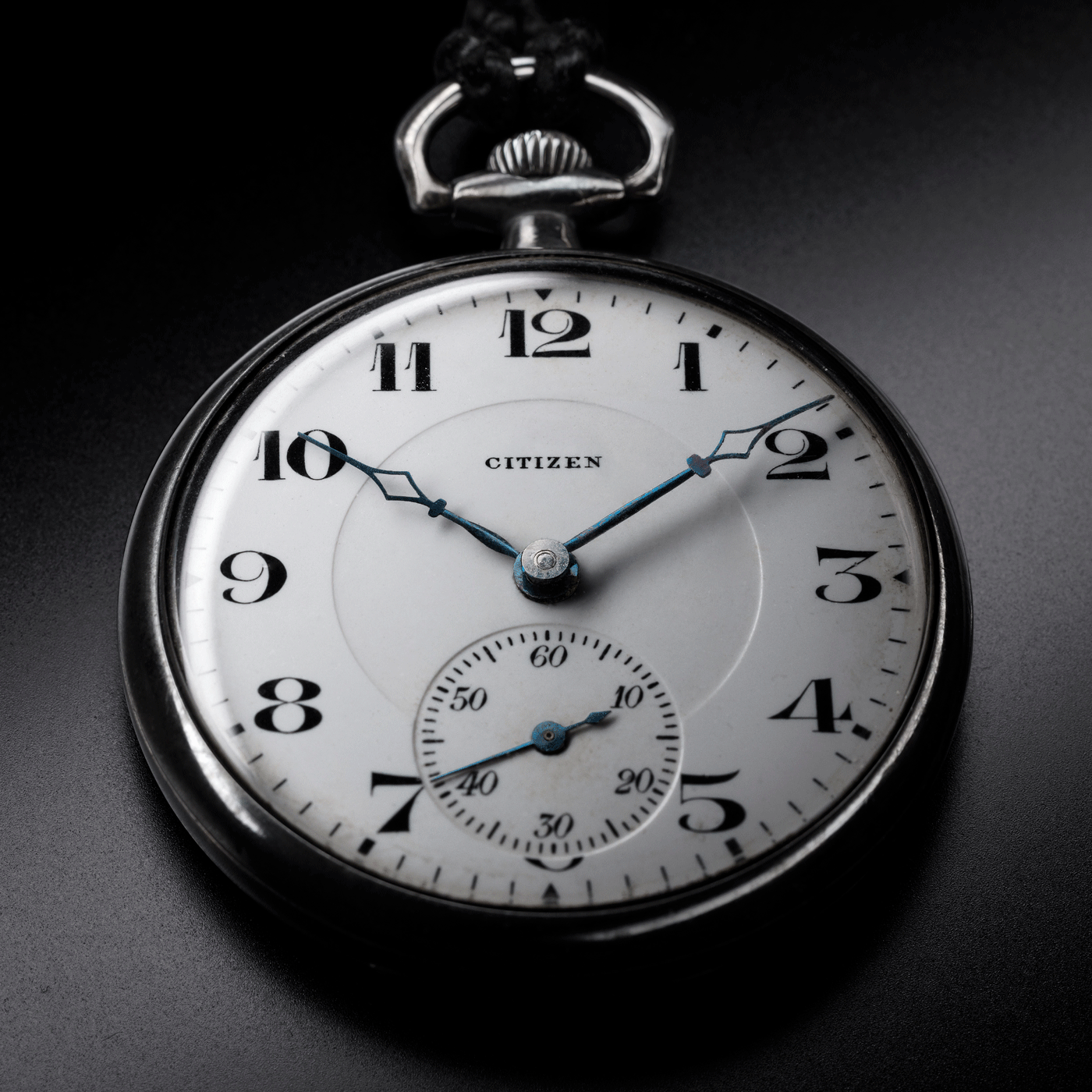 Nahaufnahme einer Citizen-Taschenuhr, die die Zeit und Details auf schwarzem Hintergrund zeigt.