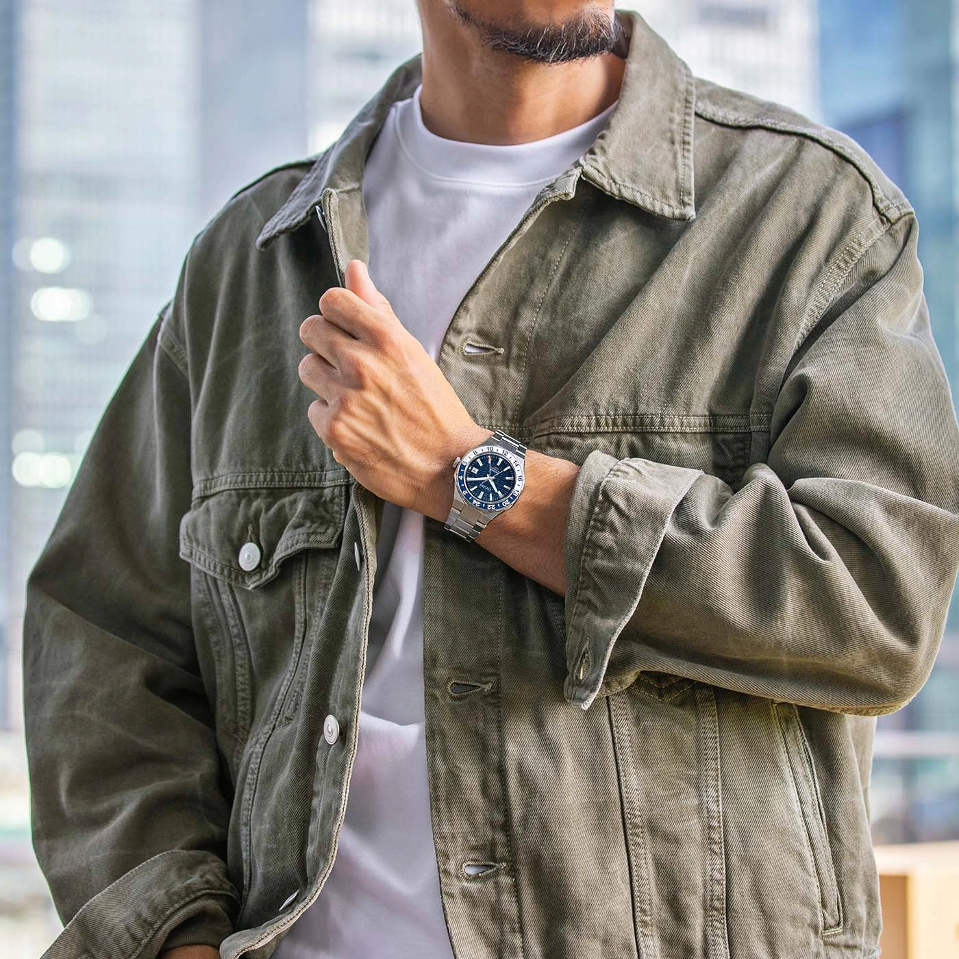 Mann mit Uhr und grüner Jacke, der für ein Foto posiert.