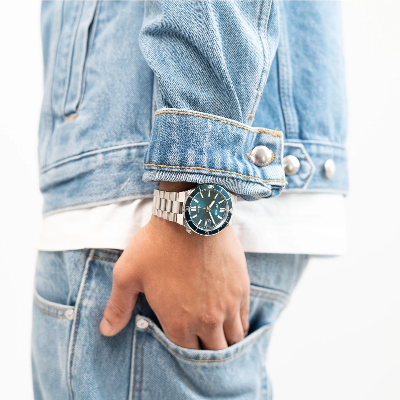 Mann trägt Jeansjacke und Jeans mit Uhr.