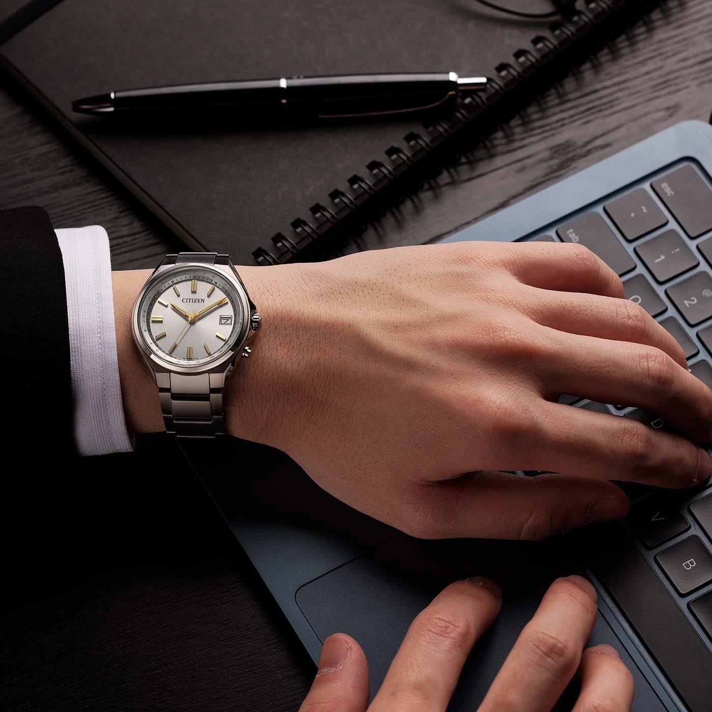 Mann mit Uhr tippt auf einem Laptop.