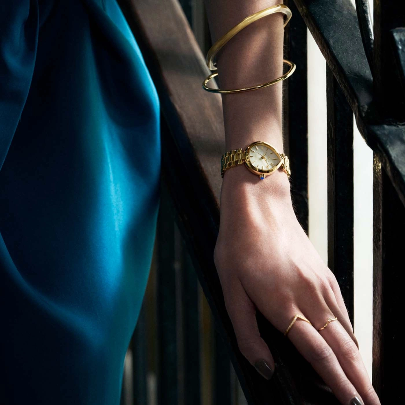 Damenhand mit Uhr, Armbändern und Ringen auf Treppen.