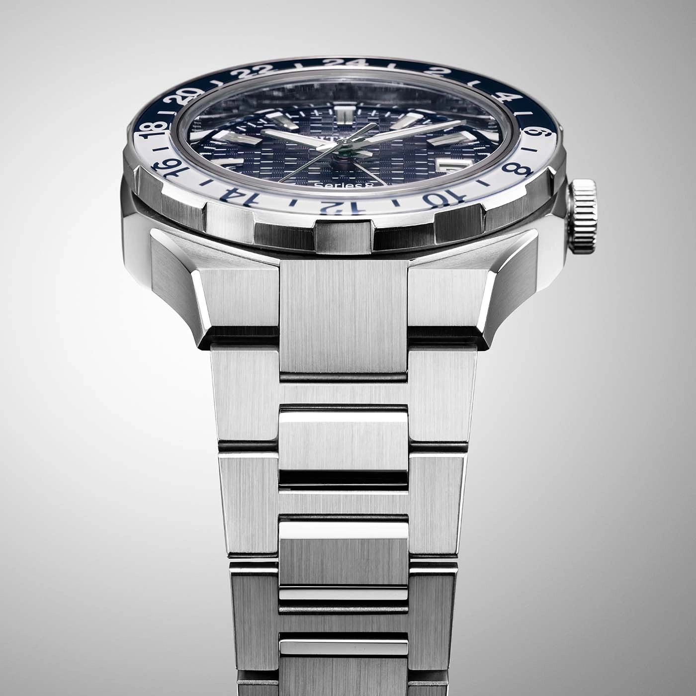 Nahaufnahme einer silbernen Uhr mit blau-weißer Lünette und Metallarmband.