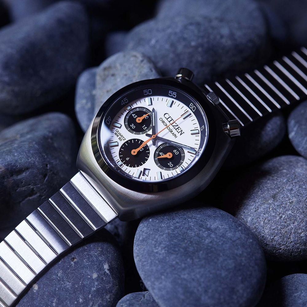 Nahaufnahme einer Citizen-Chronographenuhr auf dunklen Steinen.