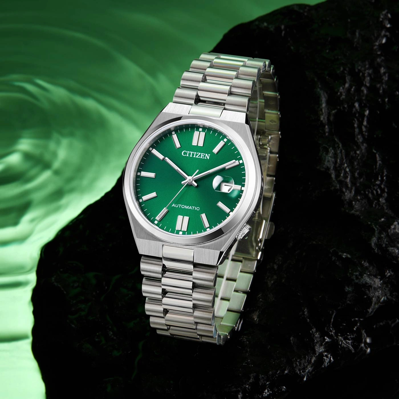 Citizen-Uhr mit grünem Zifferblatt und silbernem Armband auf dunkler Oberfläche.