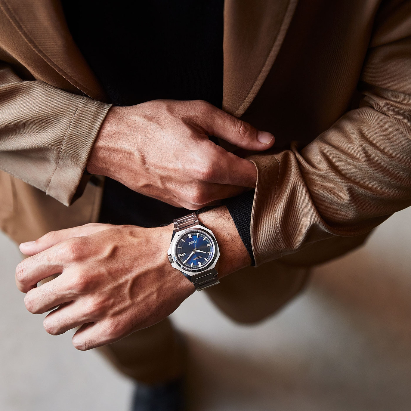 Mann mit Uhr, Anzugjacke und schwarzem Hemd, Nahaufnahme.