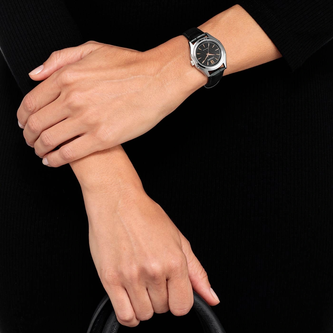 Frau mit Uhr, hält Tasche, schwarzes Kleid, Nahaufnahme, Armbanduhr