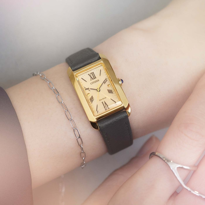 Goldene Uhr am Handgelenk mit schwarzem Armband und silbernem Armband