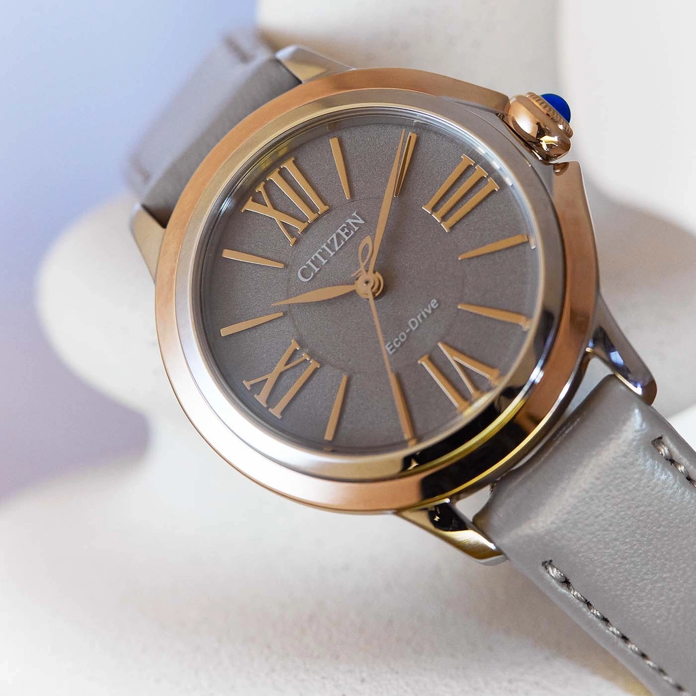 Citizen Eco-Drive Uhr mit grauem Zifferblatt und Lederarmband, goldfarbene Akzente.