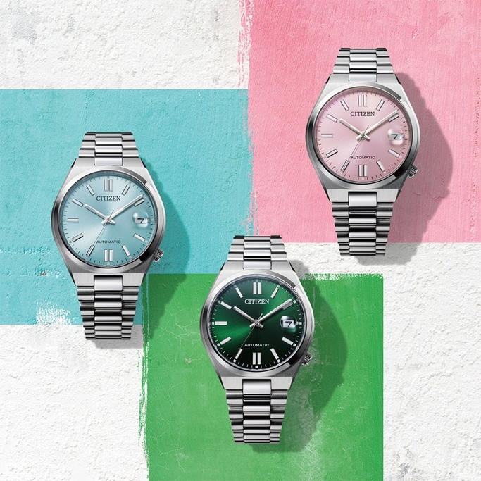 Drei Citizen-Uhren mit verschiedenfarbigen Zifferblättern auf buntem Hintergrund.