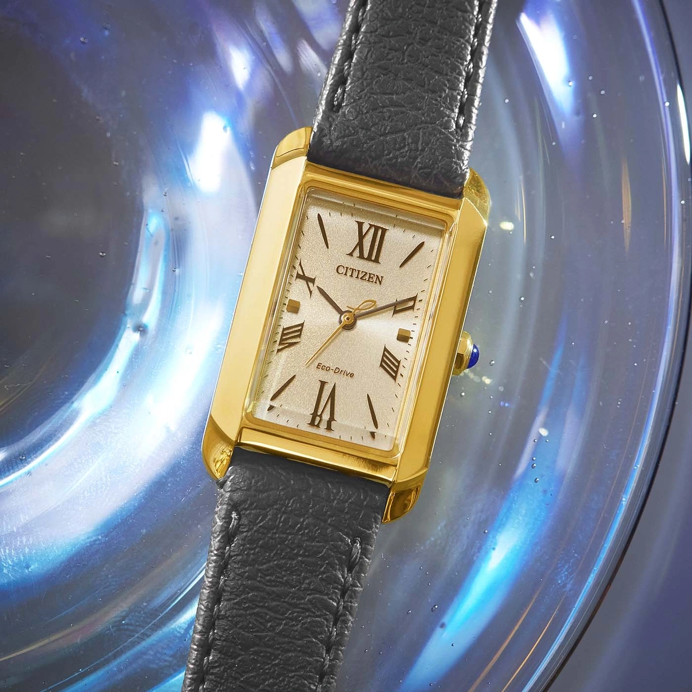 Citizen-Uhr mit goldenem Gehäuse und schwarzem Lederarmband auf blauem Hintergrund