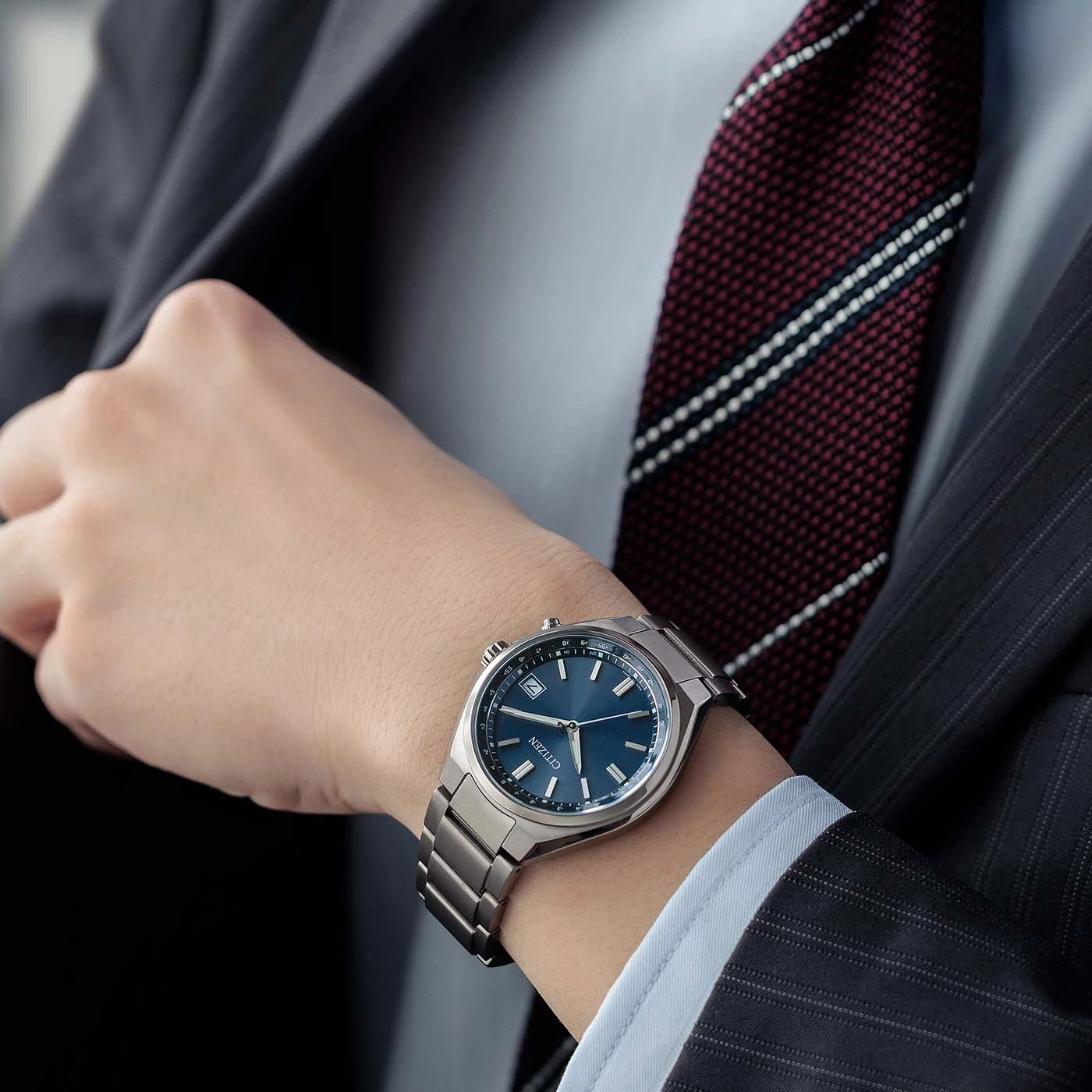 Ein Mann im Anzug trägt eine blaue Citizen-Uhr am Handgelenk.