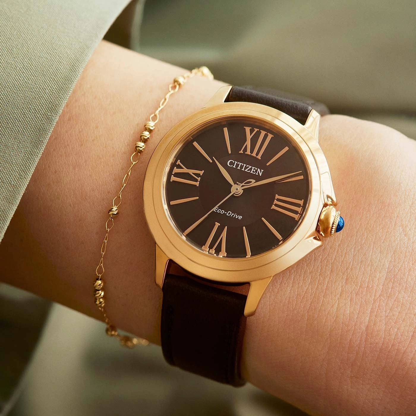 Nahaufnahme einer Citizen-Uhr am Handgelenk mit goldenem Armband.