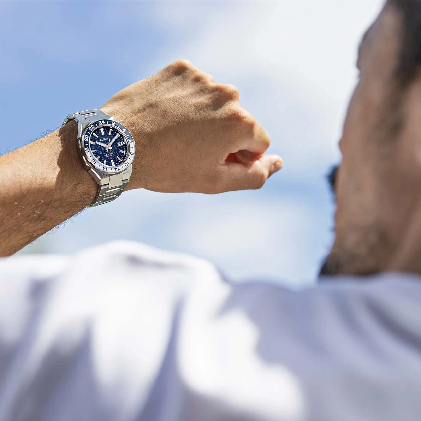 Mann schaut auf seine Uhr, blauer Himmel im Hintergrund, Citizen-Uhr