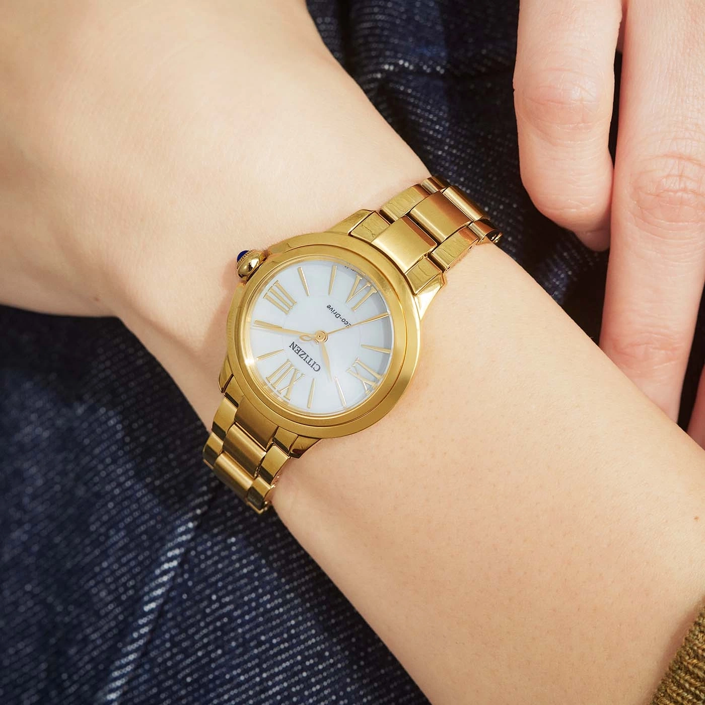 Goldene Citizen-Uhr am Handgelenk, weißes Zifferblatt, römische Ziffern, goldenes Armband, Nahaufnahme