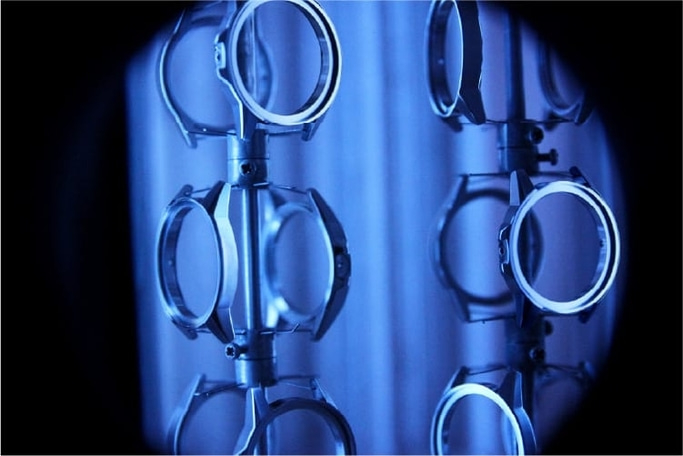 Uhrenteile auf einem Gestell, blau beleuchtet, Nahaufnahme, industrielle Szene.