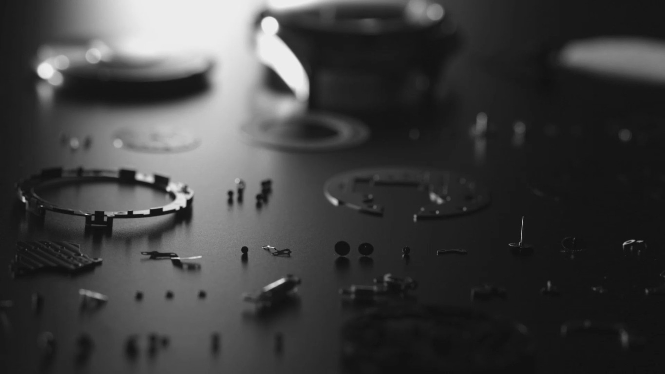 Uhrwerk-Teile auf dunkler Oberfläche zerlegt, monochrom, Nahaufnahme.