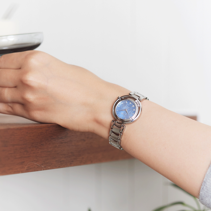 Ein Handgelenk mit einer silbernen Uhr, blauem Zifferblatt und Schneeflockenmuster.