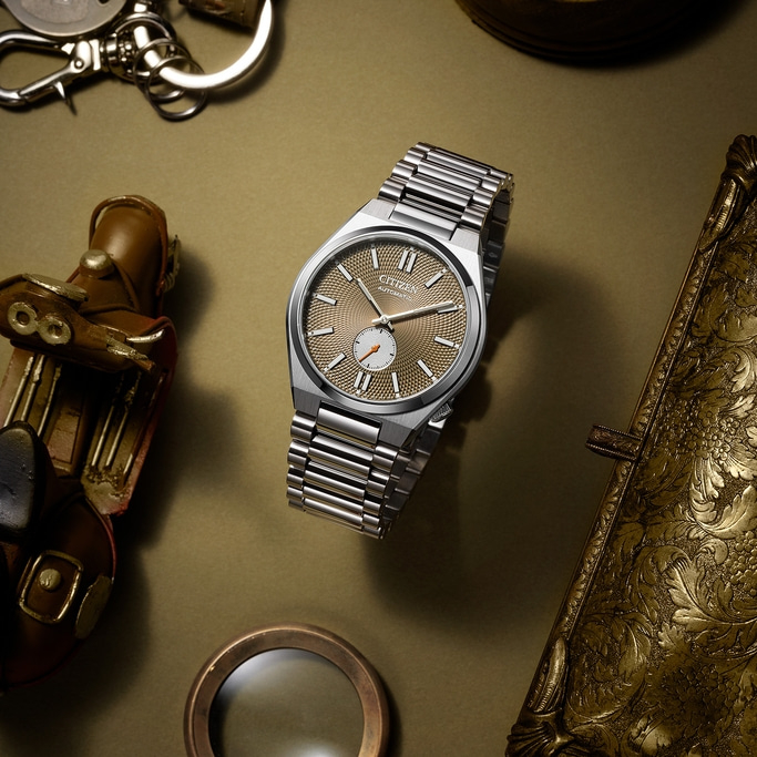 Citizen-Uhr mit goldenem Zifferblatt, umgeben von Vintage-Accessoires.