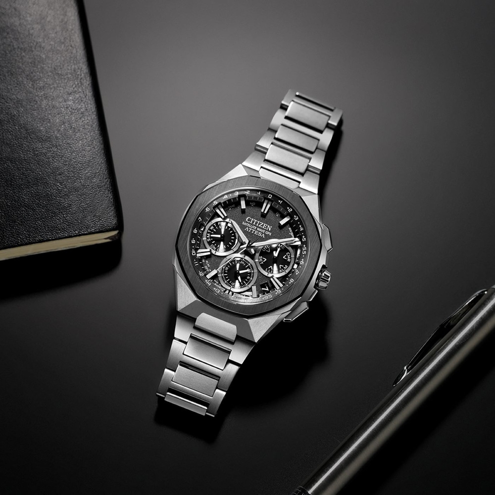 Citizen-Uhr auf schwarzer Oberfläche mit Stift und Notizbuch.