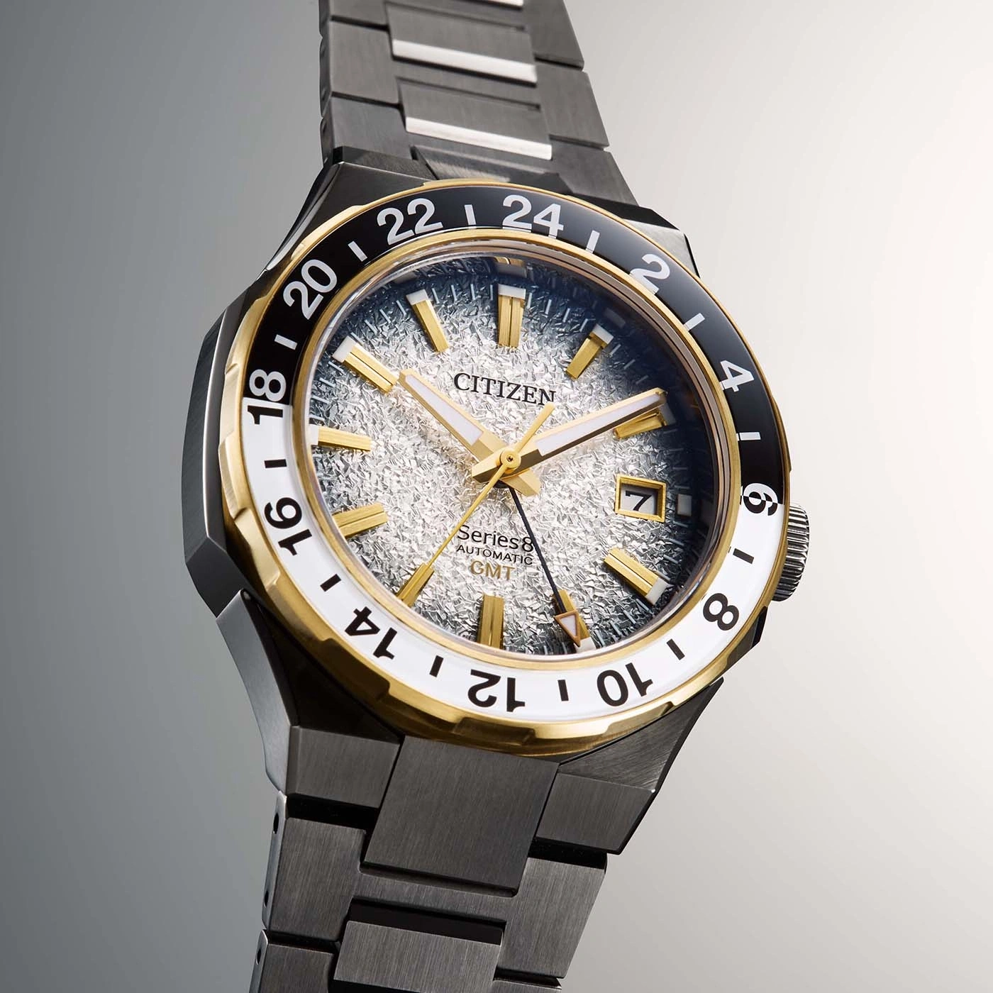 Citizen-Uhr mit goldenen Akzenten und strukturiertem Zifferblatt, GMT-Funktion.