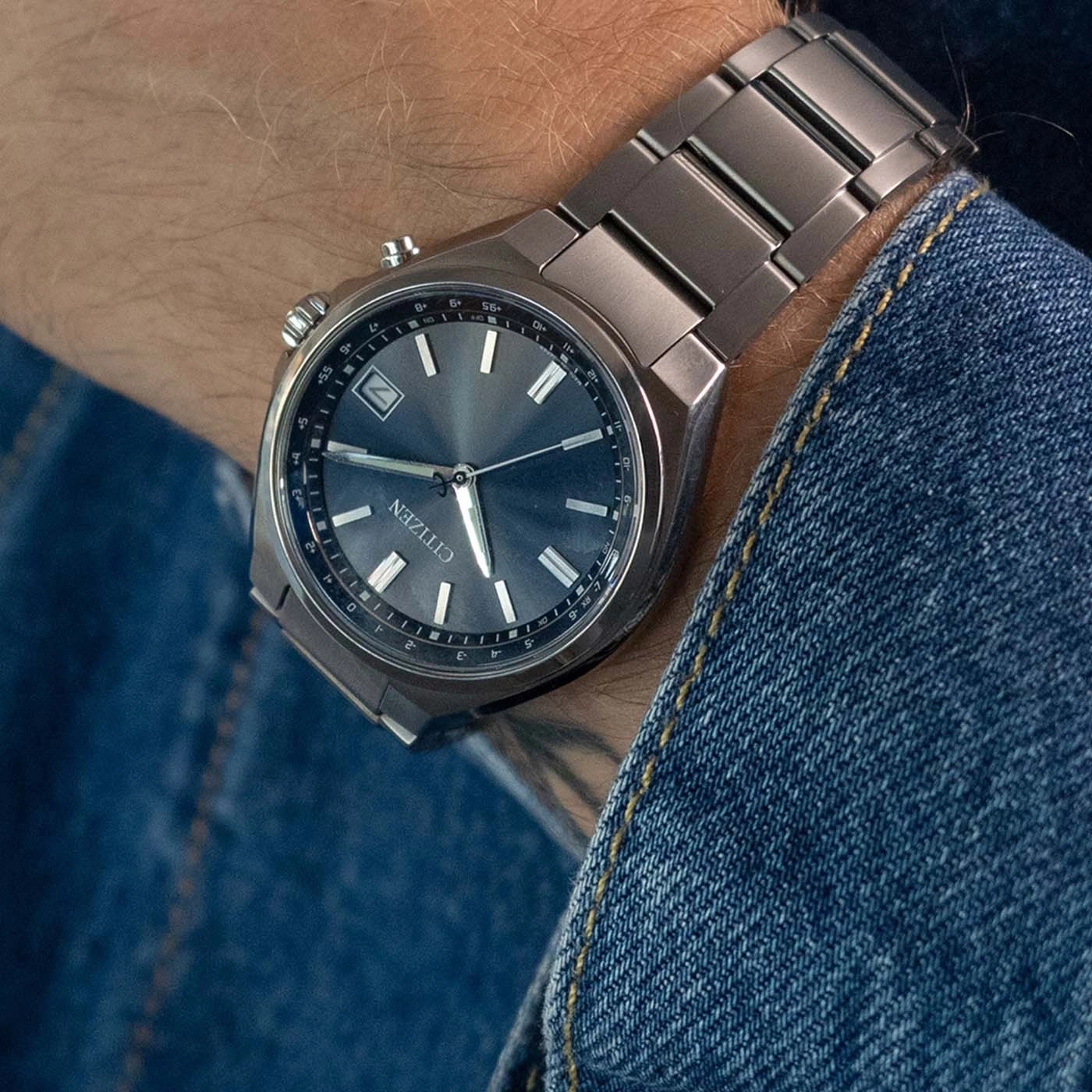 Ein Mann trägt eine Citizen-Uhr am Handgelenk, mit Zifferblatt und Metallband.