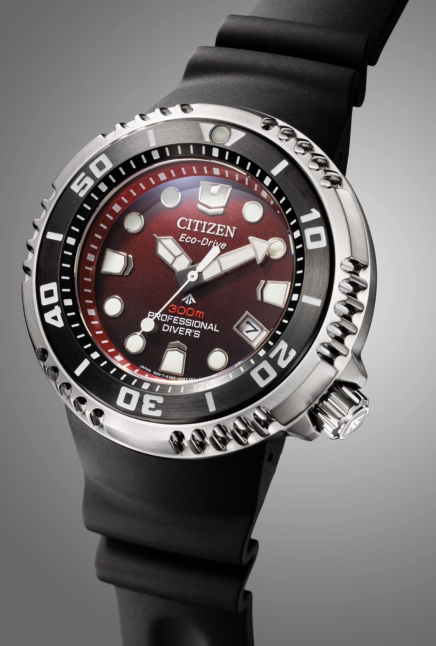 Nahaufnahme einer Citizen Eco-Drive Uhr mit rotem Zifferblatt und schwarzem Armband.