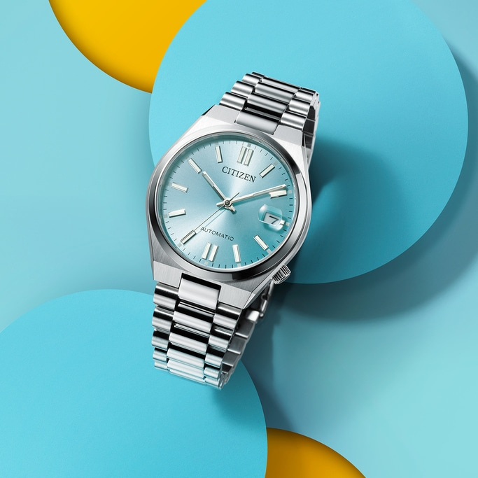 Citizen-Uhr mit hellblauem Zifferblatt auf farbenfrohem Hintergrund.