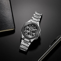 Citizen-Uhr auf schwarzer Oberfläche mit Stift und Notizbuch.
