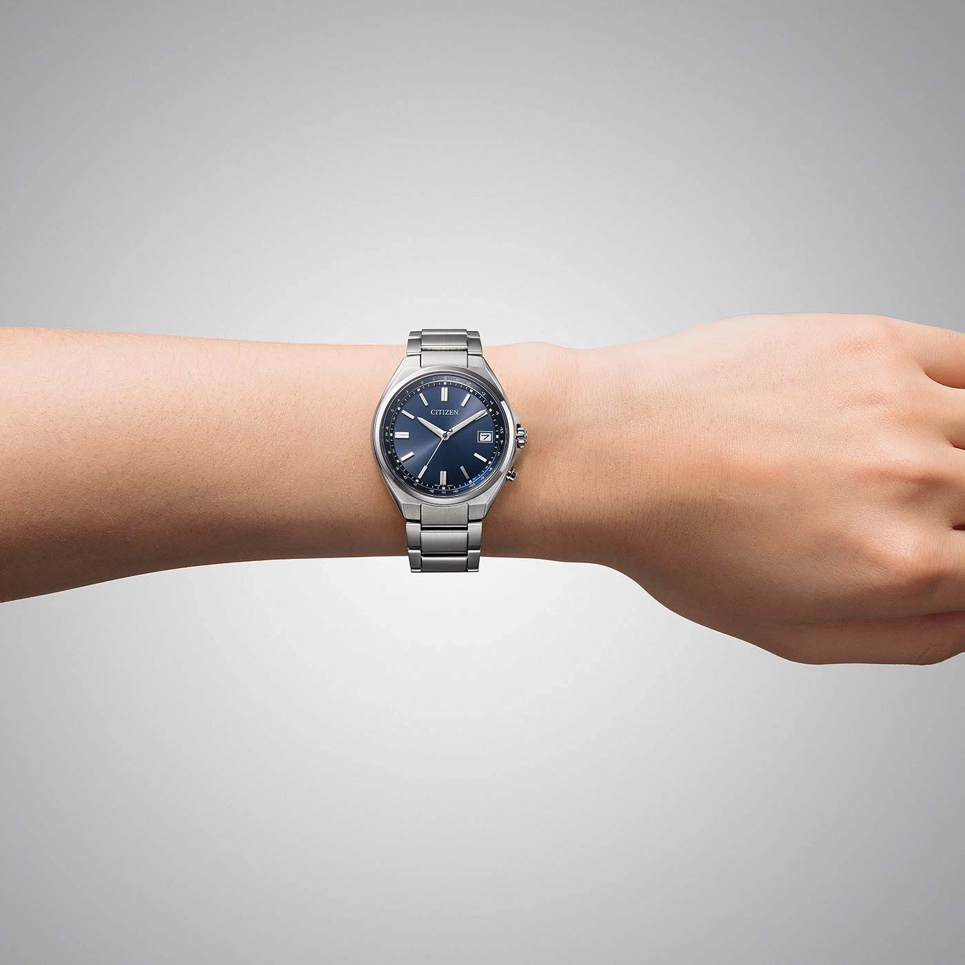 Ein Handgelenk eines Mannes mit einer silbernen Citizen-Uhr mit blauem Zifferblatt.