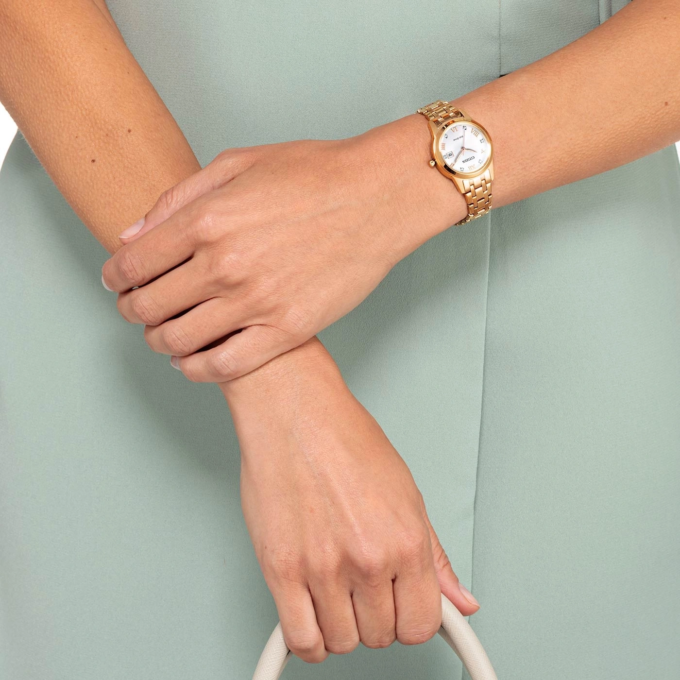 Frau mit goldener Uhr, Handtasche, hellgrünes Kleid, Nahaufnahme der Hände