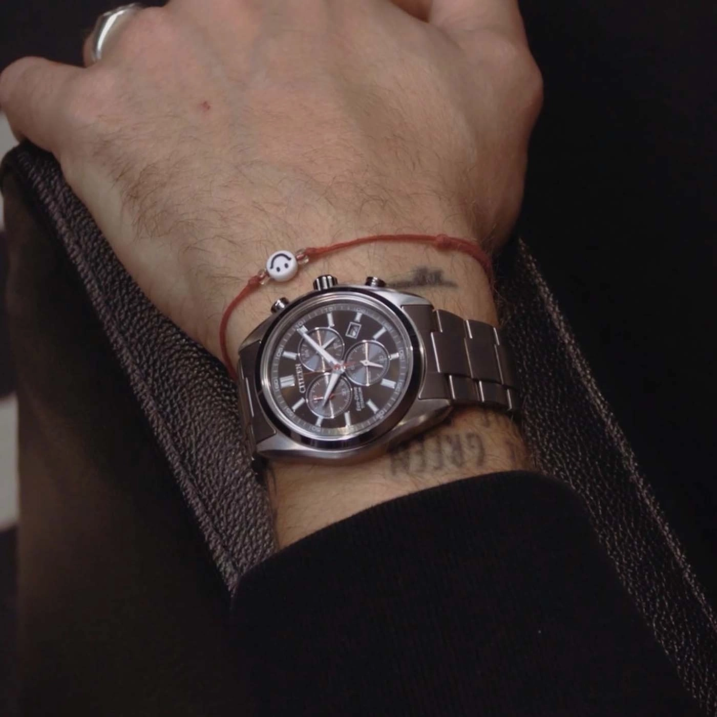 Männliches Handgelenk mit Uhr und Smiley-Armband.