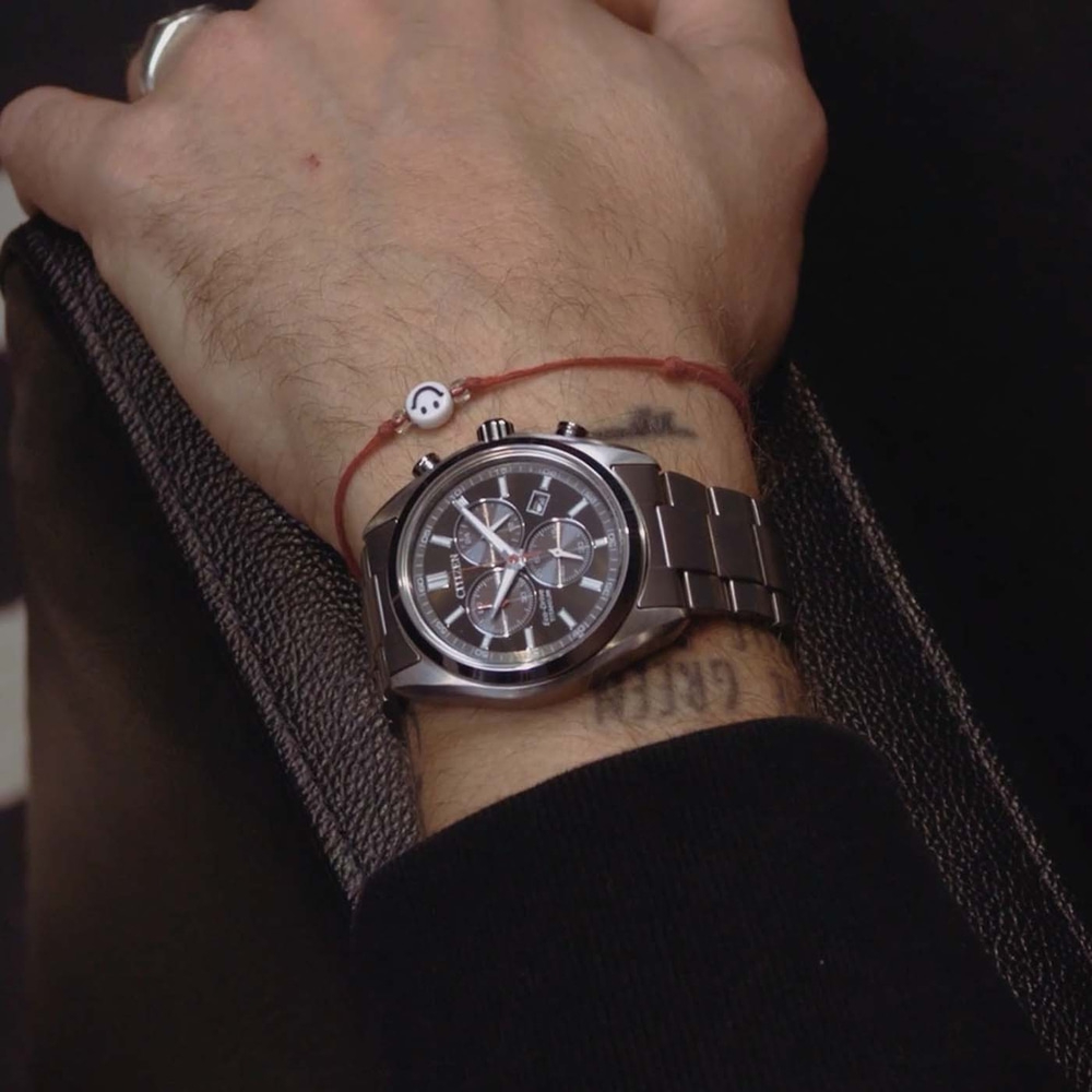 Männliches Handgelenk mit Uhr und Smiley-Armband.