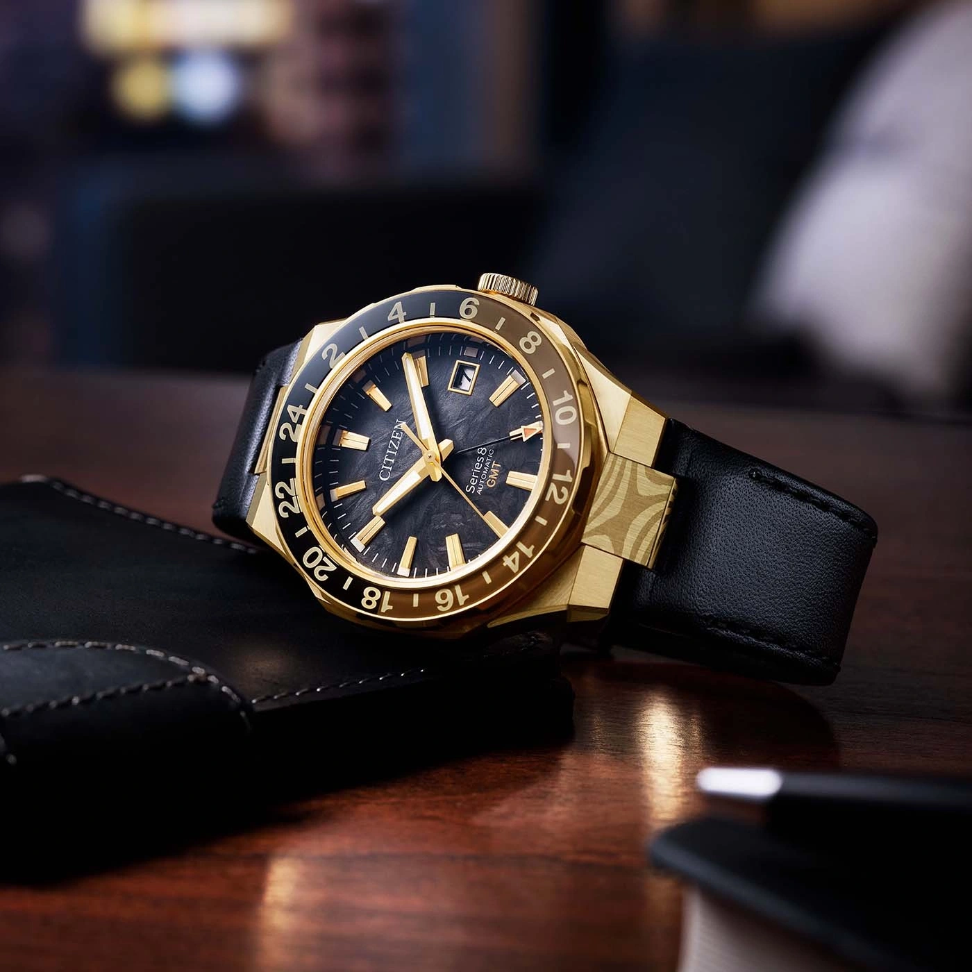 Eine goldene Citizen GMT-Uhr mit schwarzem Zifferblatt und Lederarmband.