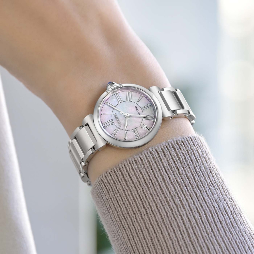 Das Handgelenk einer Frau trägt eine silberne Uhr mit einem Perlmuttzifferblatt.