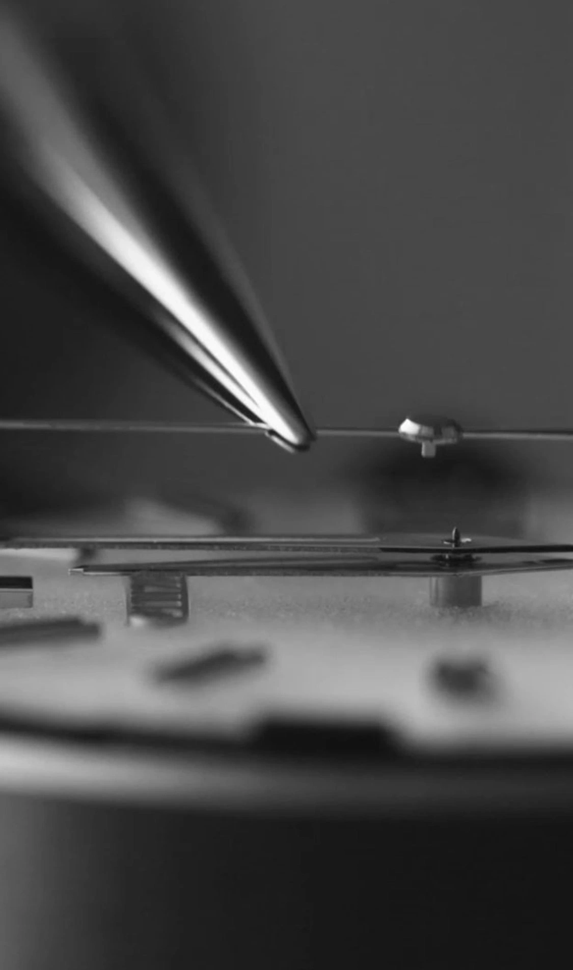 Nahaufnahme des Uhrenmechanismus mit Werkzeug, Schwarzweiß, detailliert.