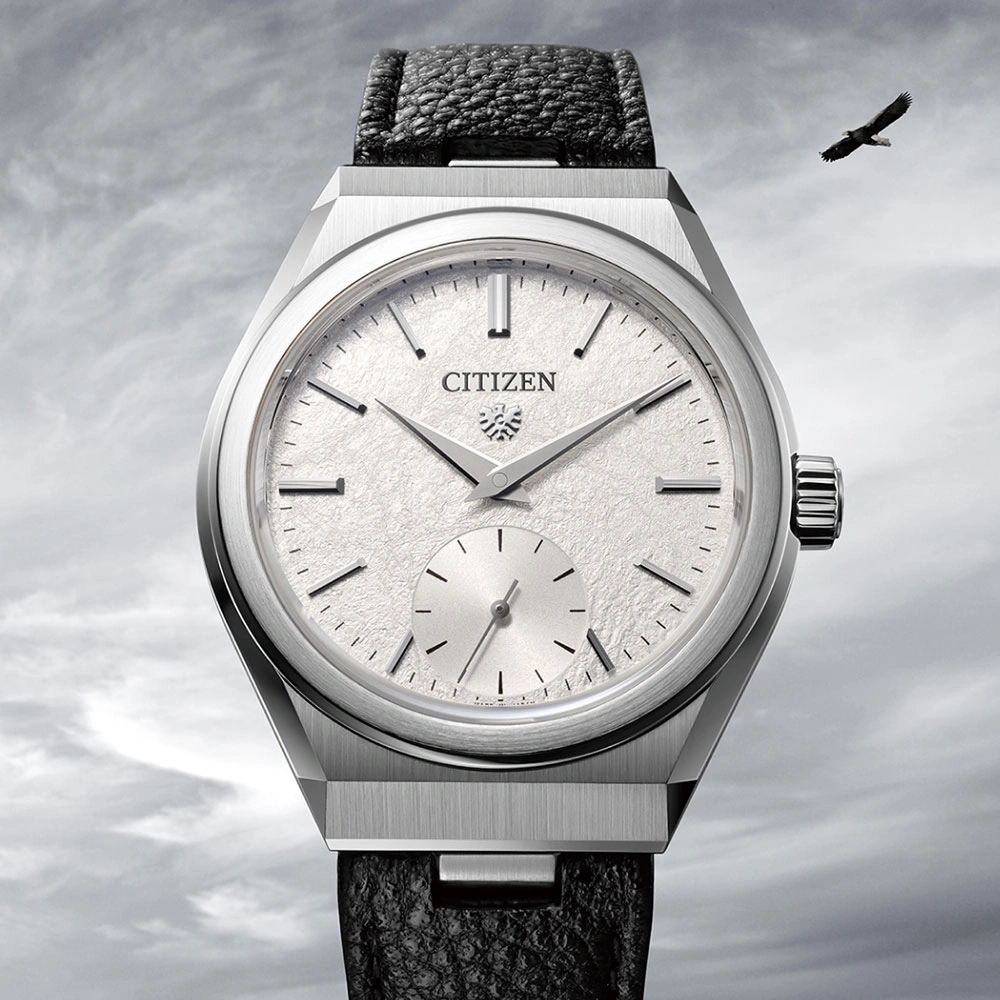 Citizen-Uhr mit strukturiertem Zifferblatt und schwarzem Lederarmband, Adler im Hintergrund.