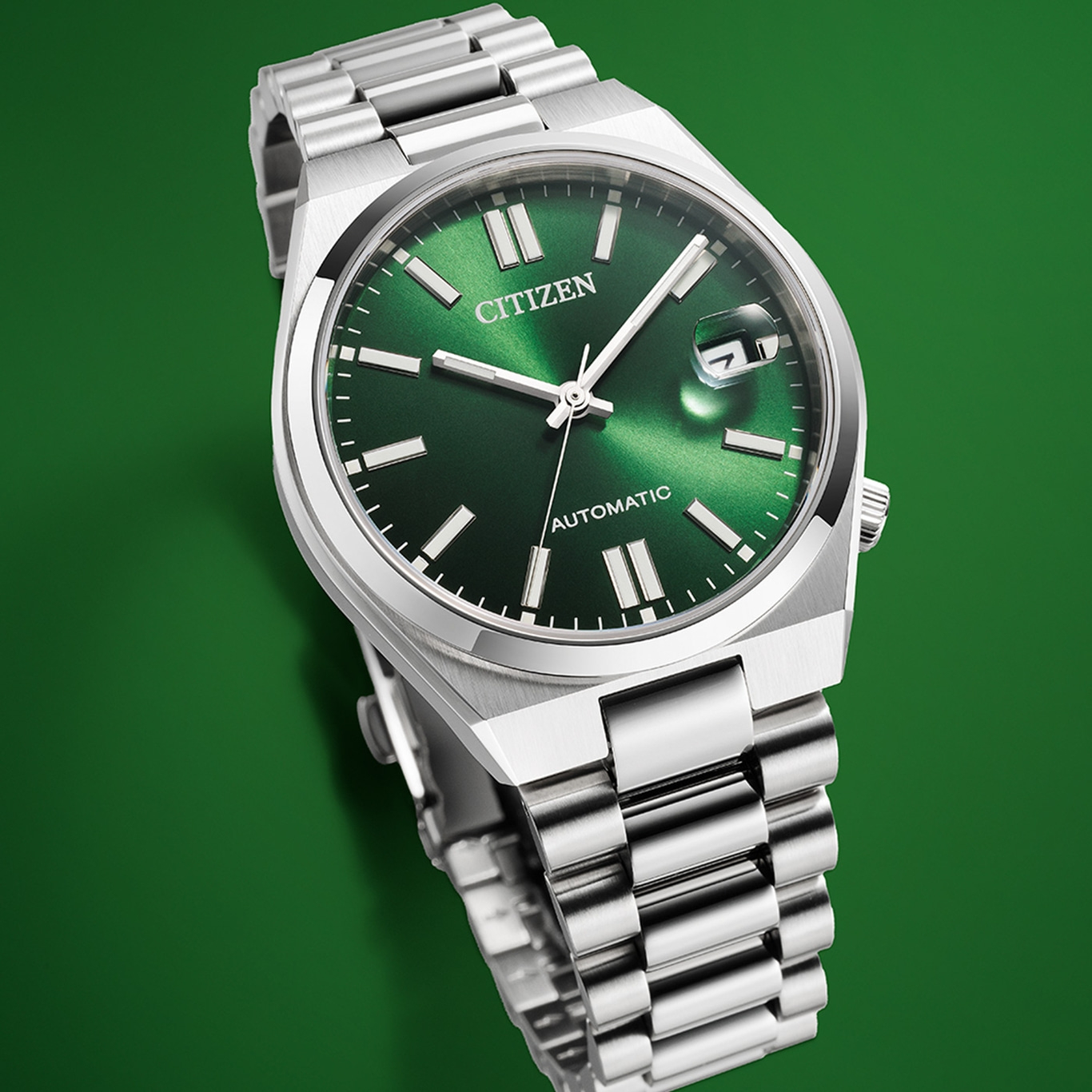 Citizen-Uhr mit grünem Zifferblatt und silbernem Armband auf grünem Hintergrund.