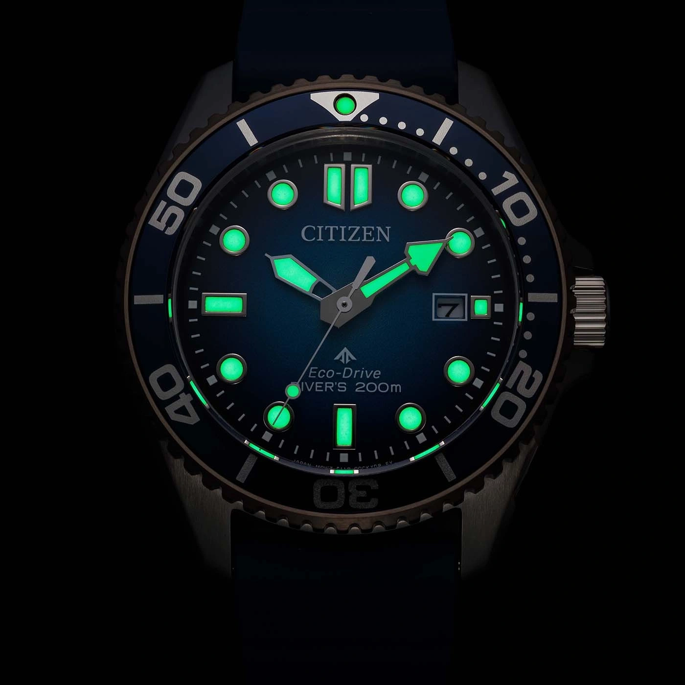 Nahaufnahme einer leuchtenden blauen Citizen Eco-Drive Taucheruhr bei Nacht mit leuchtenden Markierungen und Zeigern.