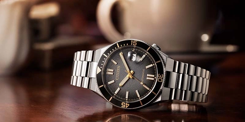 Eine klassische Citizen Automatik-Uhr mit dunklem Zifferblatt und goldenen Akzenten, auf einer Holzoberfläche.