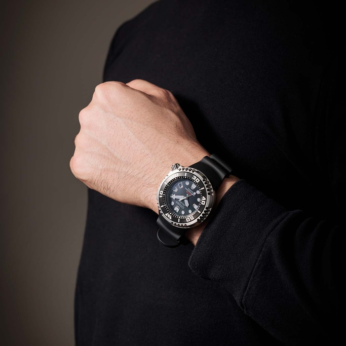 Mann trägt schwarze Uhr am Handgelenk, Nahaufnahme. Schwarzer Pullover.