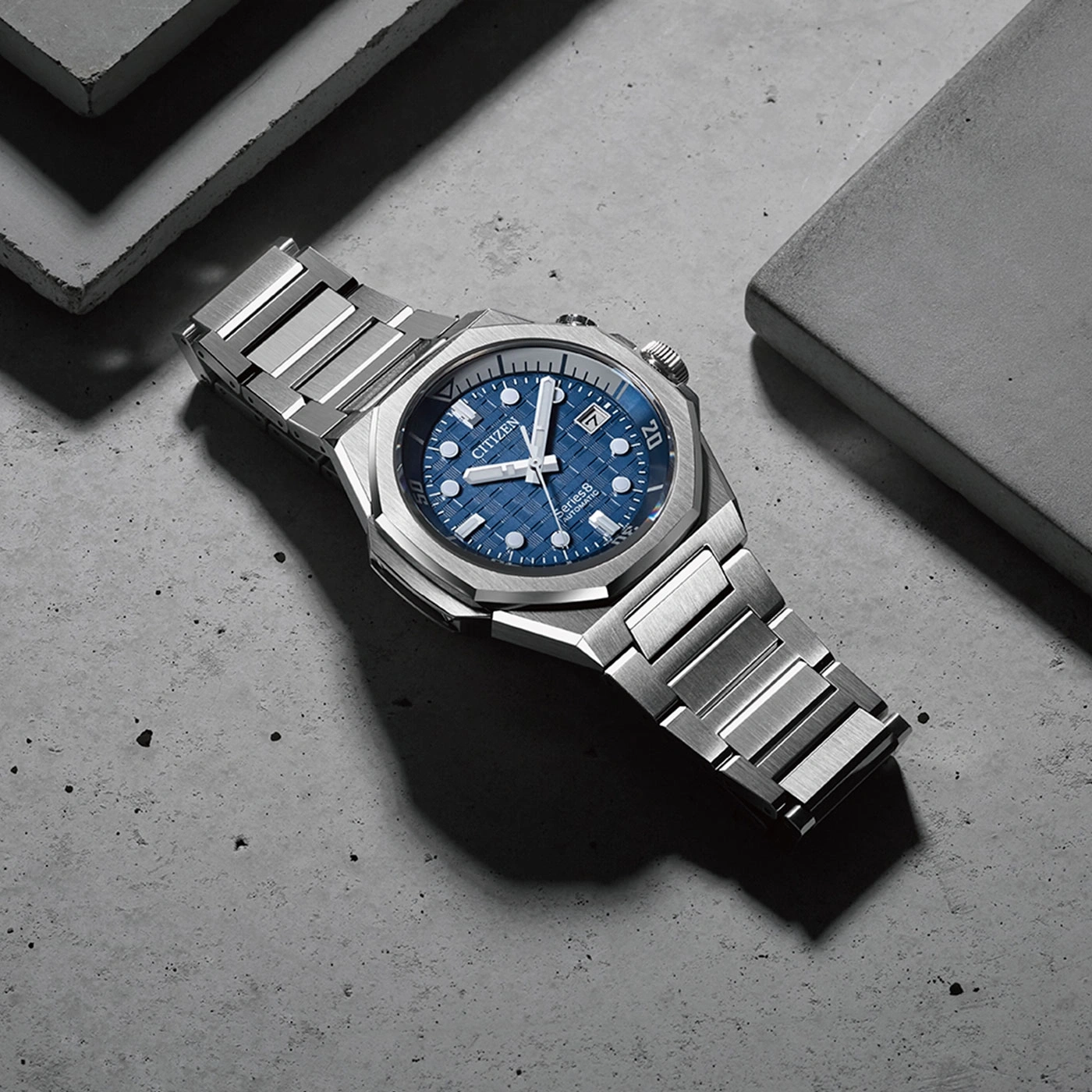 Citizen-Uhr mit blauem Zifferblatt und silbernem Armband auf Betonoberfläche
