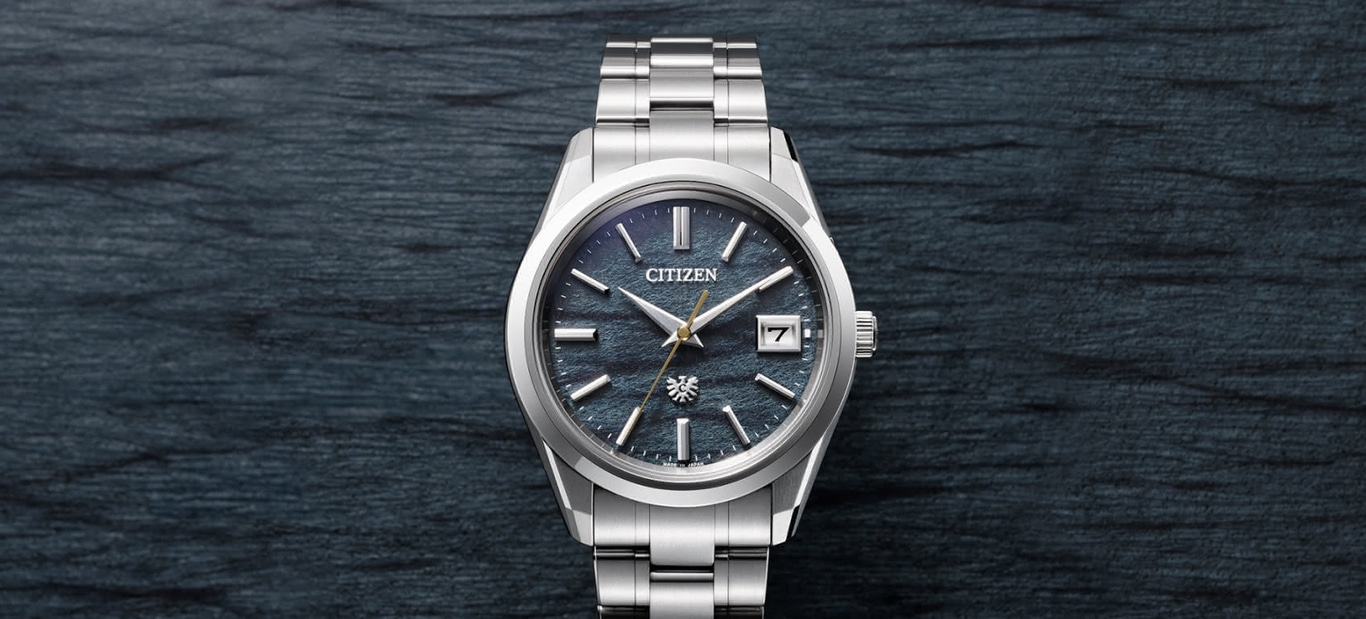 Citizen-Uhr mit dunkelblauem Zifferblatt und silbernem Armband auf dunklem Hintergrund.