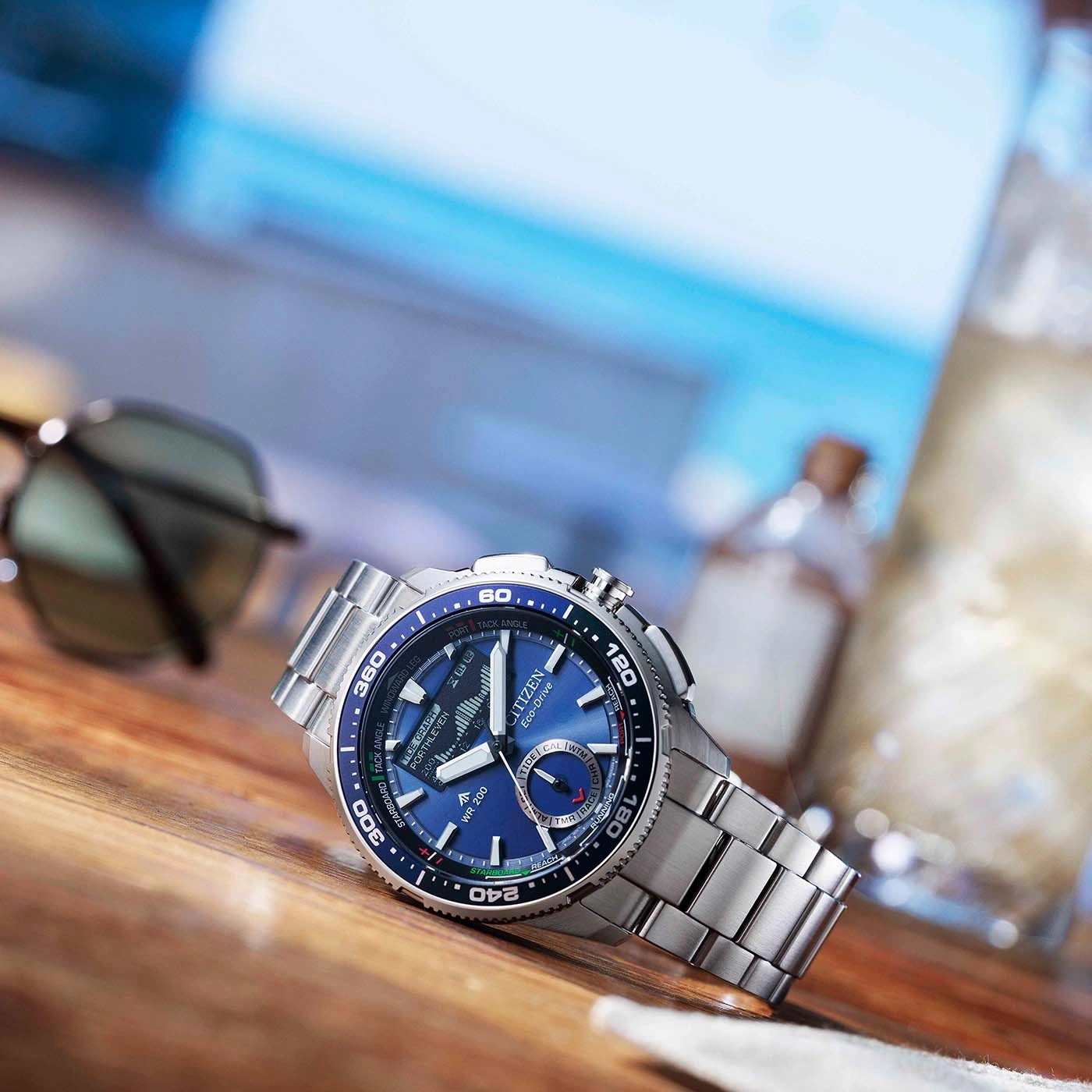 Eine blaue Citizen Eco-Drive Uhr auf einem Holztisch mit Sonnenbrille.