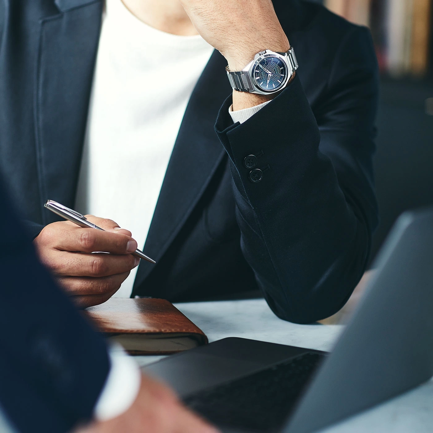 Mann im Anzug mit Uhr und Stift, arbeitet am Laptop, Geschäftstreffen.