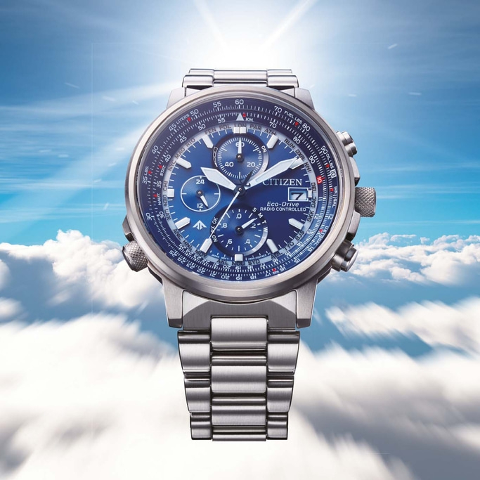 Citizen-Uhr mit blauem Zifferblatt, silbernem Armband und mehreren Zifferblättern vor Wolkenhimmel.