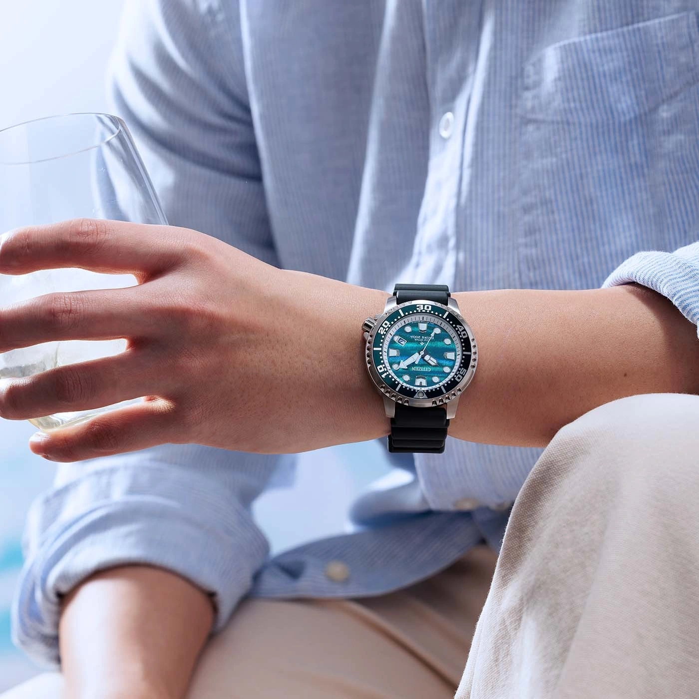 Ein Männerhandgelenk trägt eine blaue Citizen-Uhr mit schwarzem Armband.
