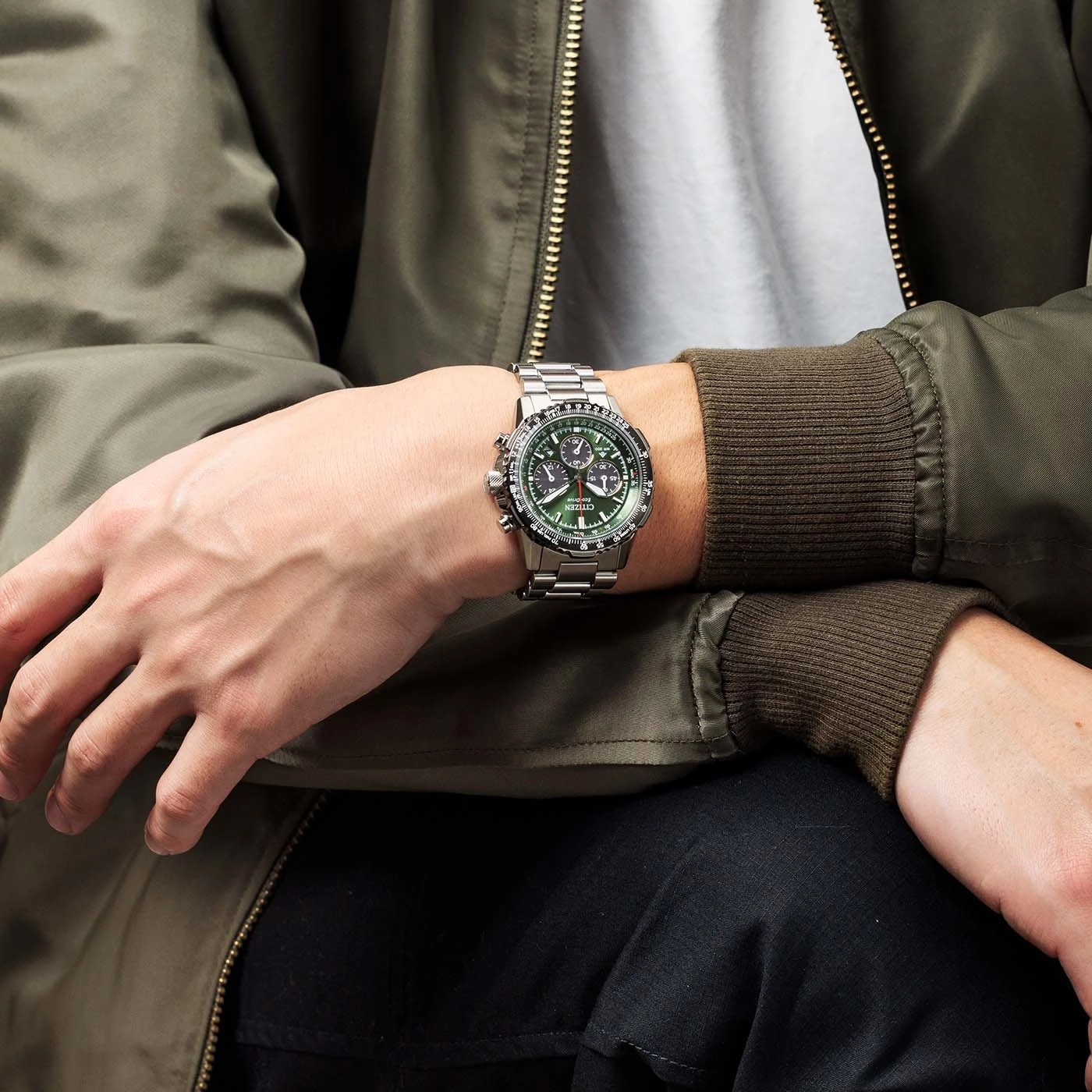 Mann mit silberner Uhr und grünem Zifferblatt, grüne Jacke, Nahaufnahme.