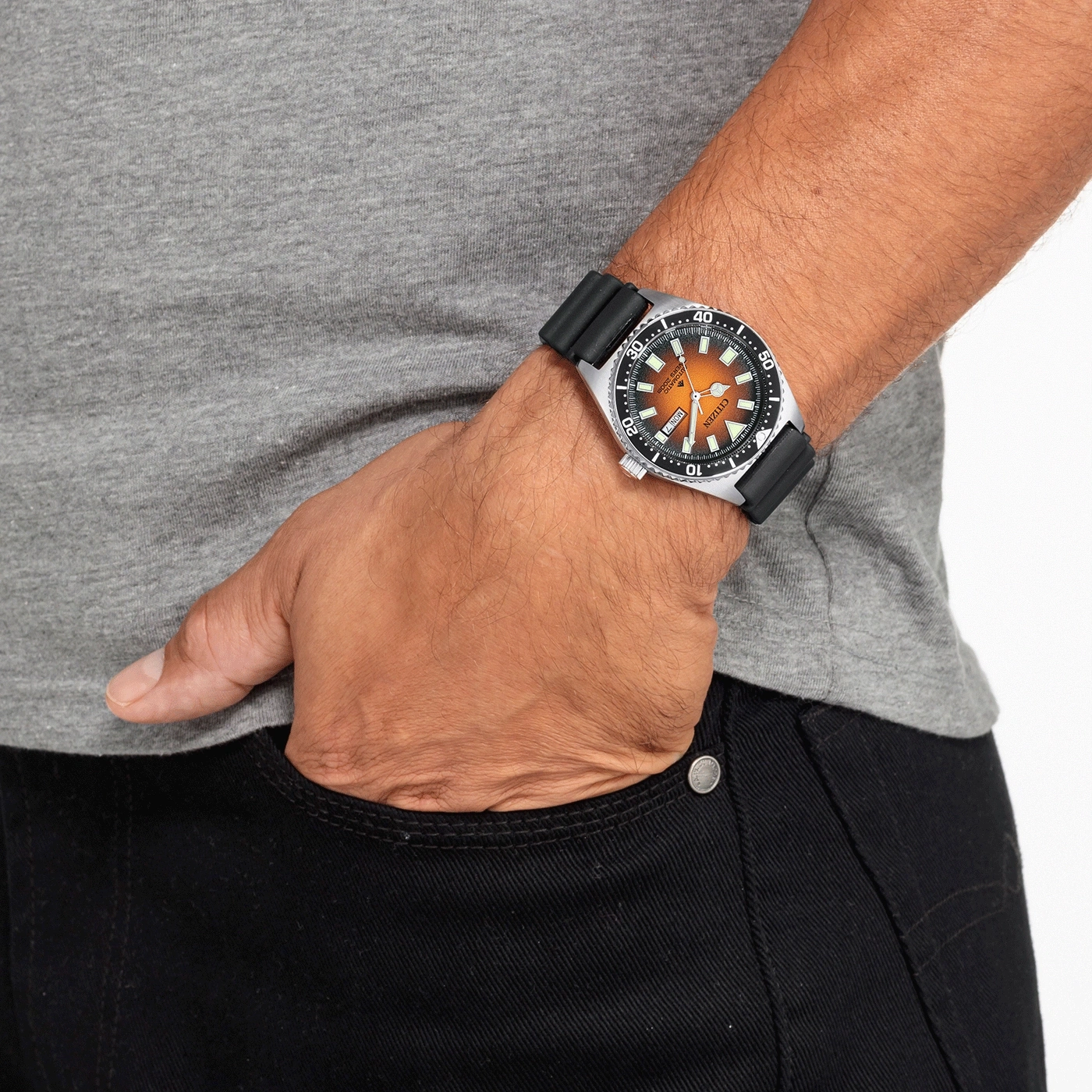 Mann mit Uhr, Hand in der Tasche, graues Hemd, schwarze Jeans.